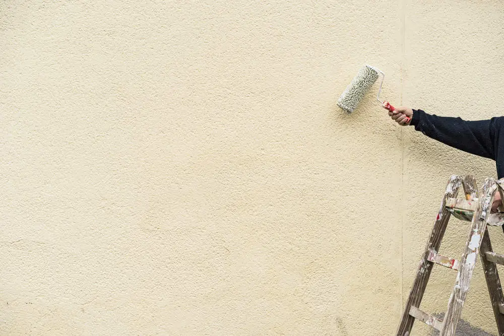 Heimwerker streicht die Hausfassade