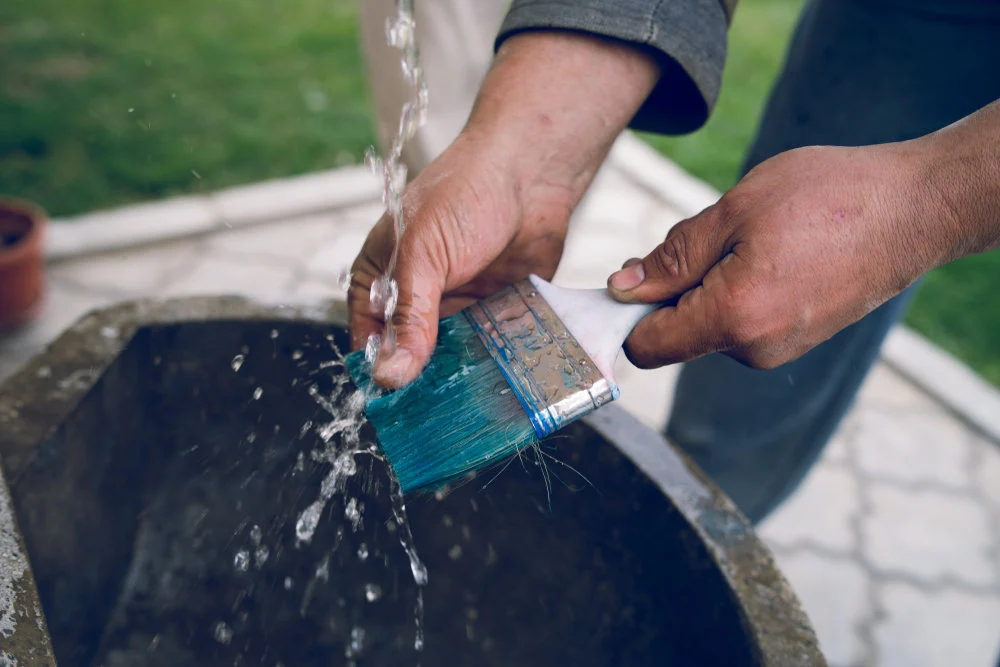 Mann reinigt schmutzigen Pinsel unter fliessendem Wasser